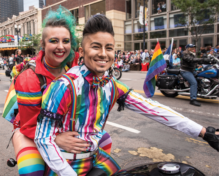 A boy and a girl riding a motorcycle at the Twin Cities Pride parade.