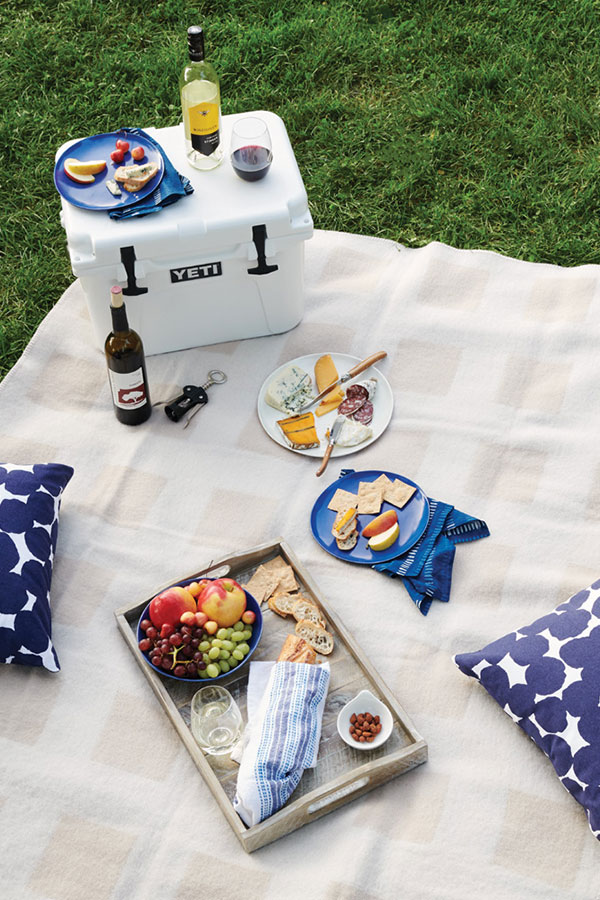 A picnic set up with wine, food, and pillows.