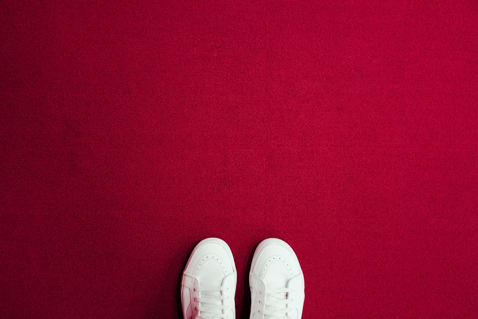 White sneakers on a red carpet. Photo by Christian Chen/Unsplash.