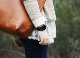 A woman with a smartwatch in the park with a leather shoulder bag