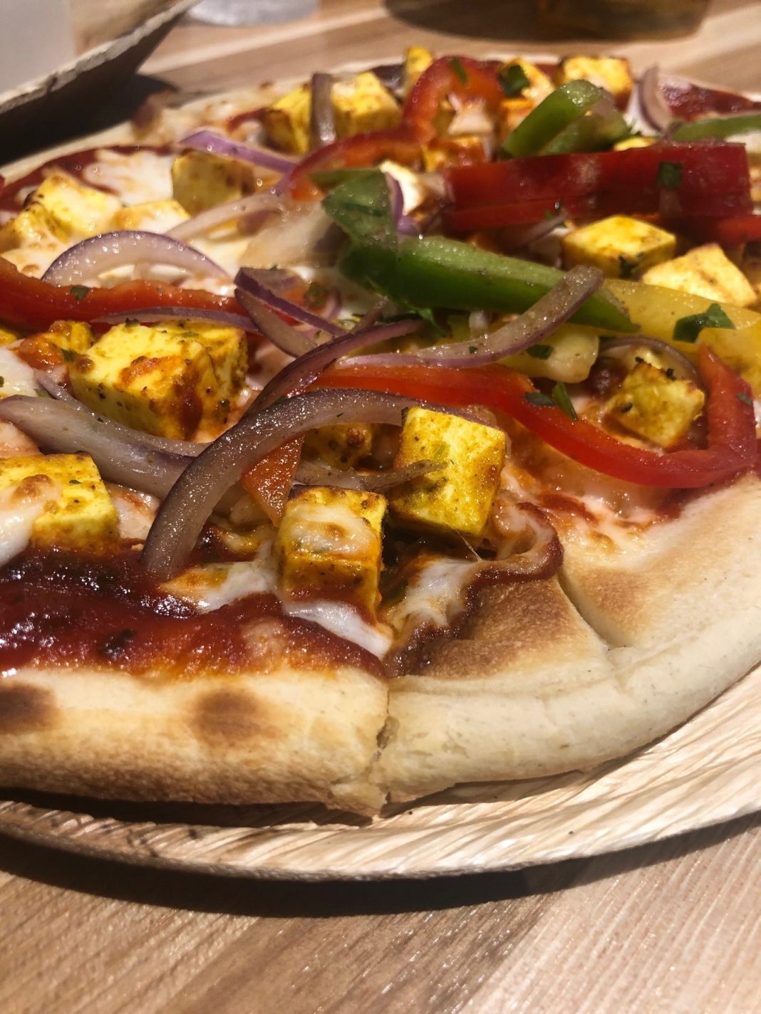 Paneer Pizza ($10) with non-melting cheese marinated in Greek yogurt, lime-kissed peppers, tomato-fenugreek sauce, and fresh mozzarella on plain naan