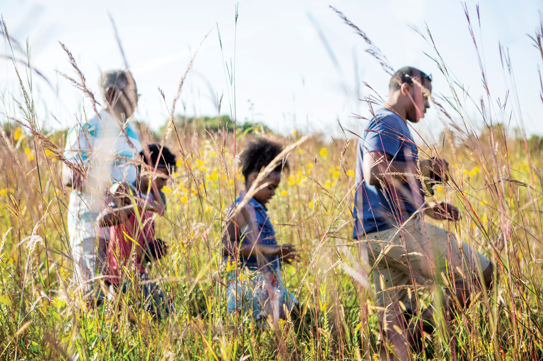 A family walks through the tall prairie grass in Blue Mounds State park