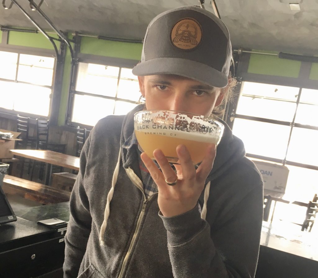 Person staring at the camera, drinking out of a Back Channel Brewing beer bowl