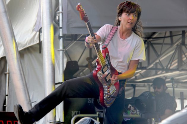 Courtney Barnett performs at Rock the Garden, balancing on one foot as she plays her signature red guitar.