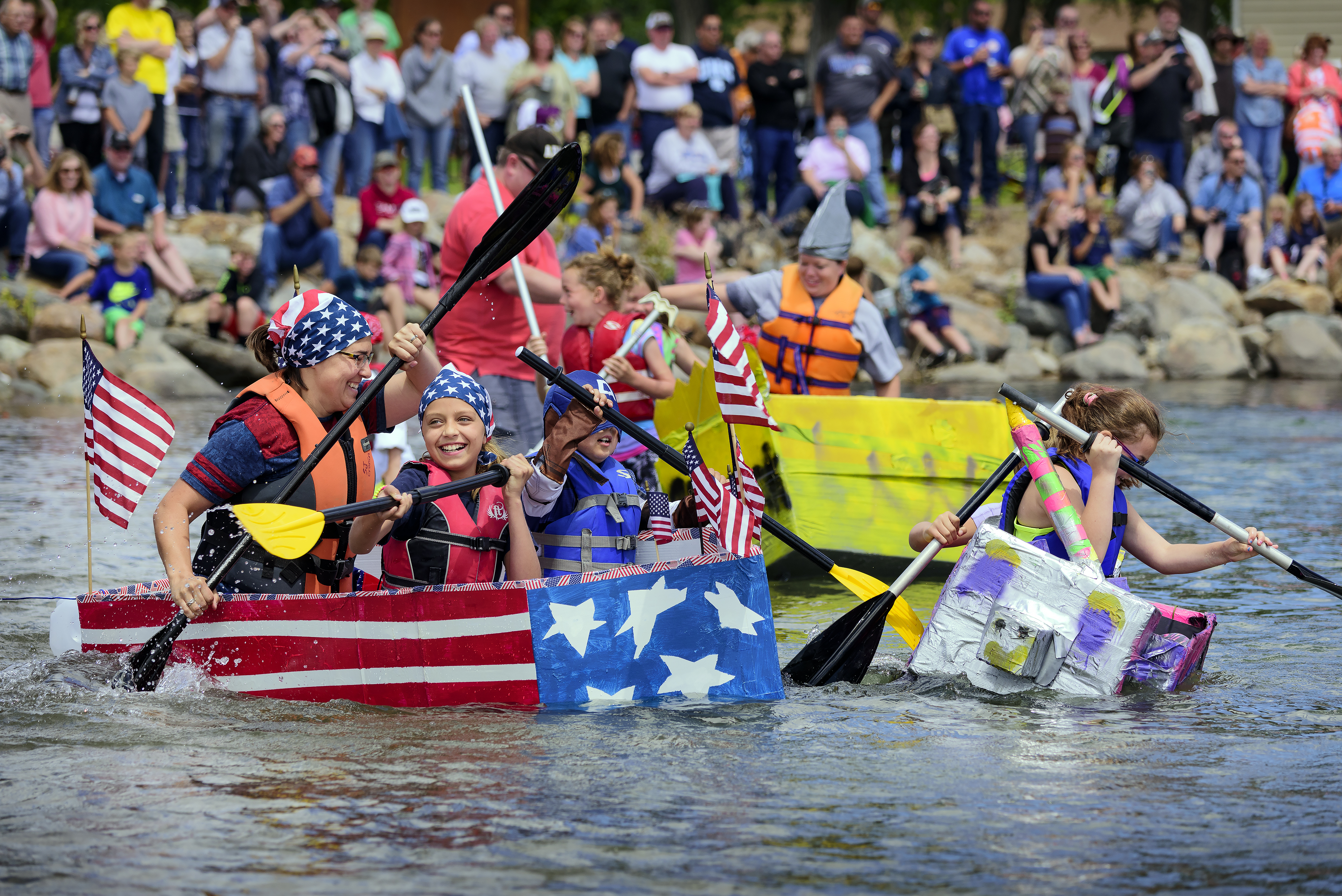 People rowing an American flag themed cardboard boat at Oahe Days in South Dakota