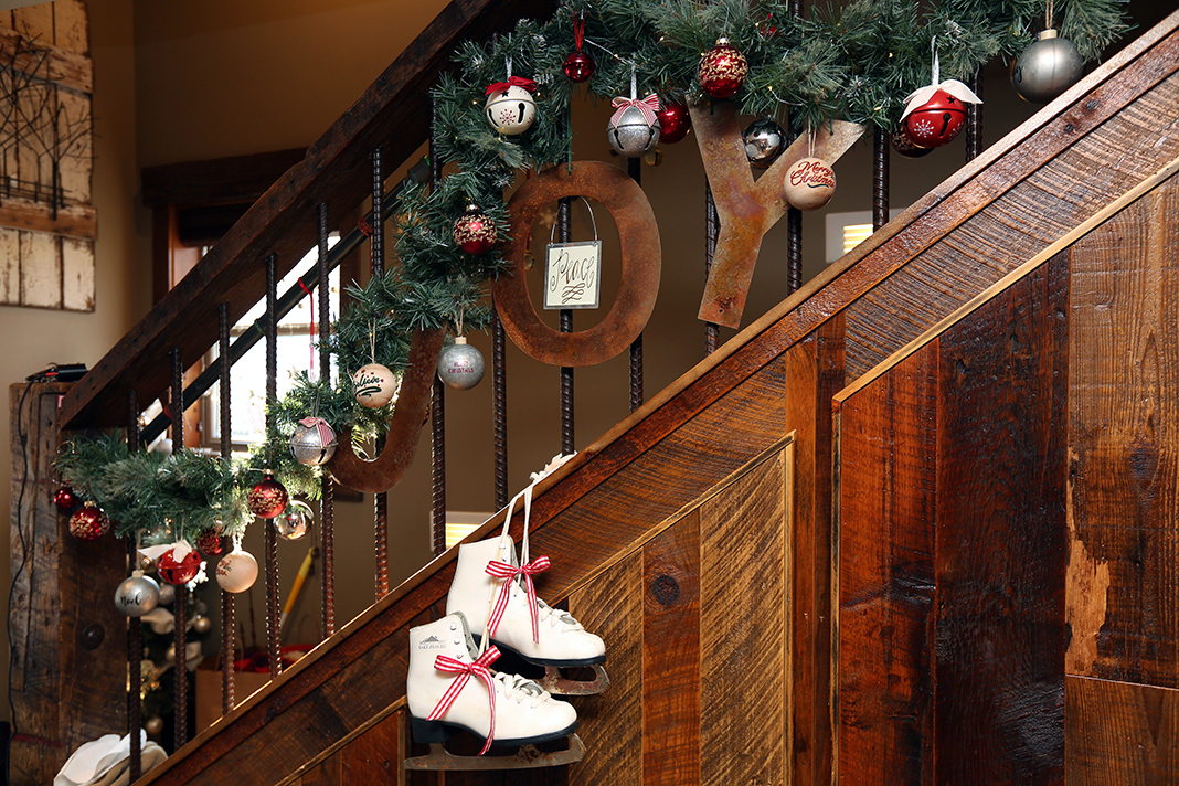 A wooden stairwell with garland, ornaments, and a pair of ice skates as holiday decorations