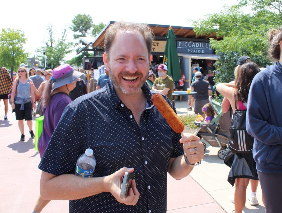 Jason DeRusha eating a tater tot dog at the Minnesota State Fair