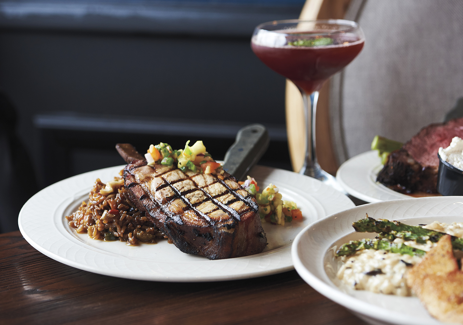 Clockwise from left: A beautiful bone-in pork chop topped with pineapple salsa, Creole Williams cocktail, Porterhouse Steak, Seared Walleye fillet with mushroom risotto and asparagus