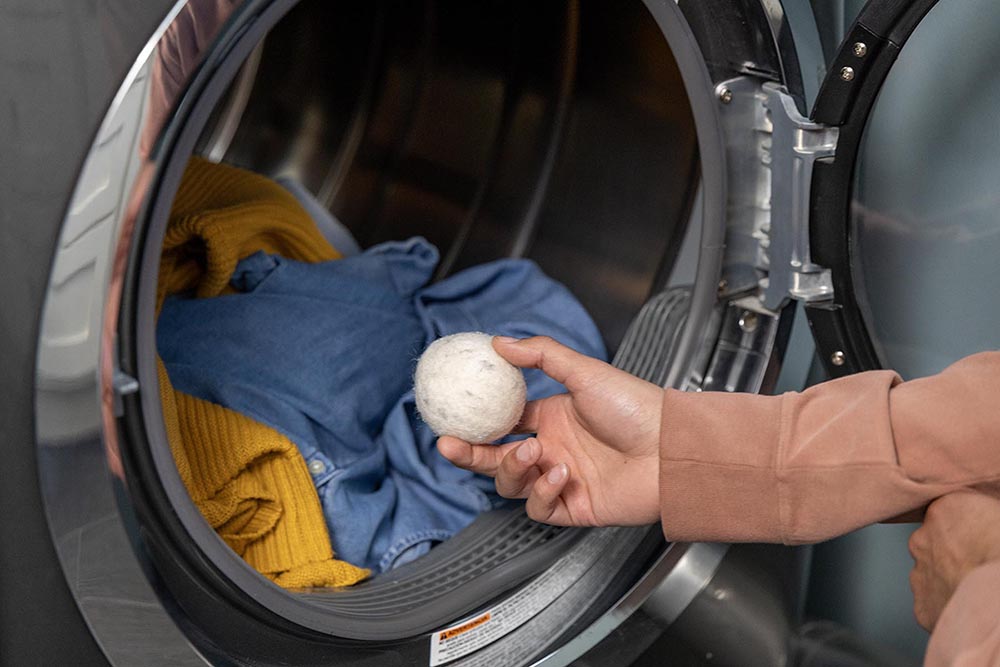 woman placing dryer ball into load of laundry