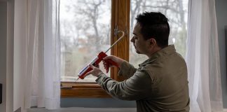 Man sealing window with Caulk