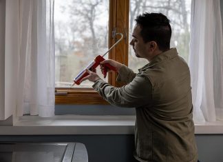 Man sealing window with Caulk