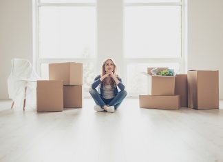 Portrait of young pretty woman sitting on the floor and thinking how to unpack all the stuff
