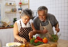 Happiness senior elderly couple having fun in kitchen with healthy food for working from home